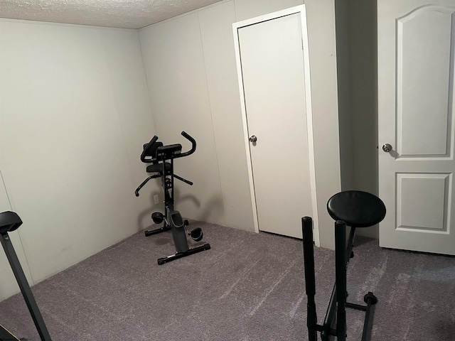 exercise room featuring dark carpet and a textured ceiling