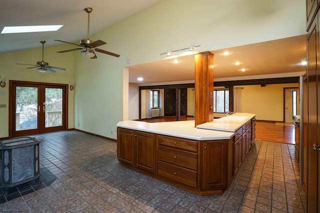 kitchen with french doors, a skylight, ceiling fan, sink, and a wood stove