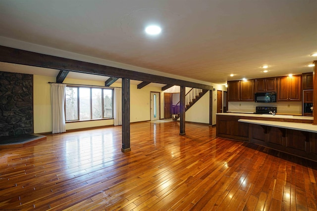 kitchen with beamed ceiling, dark wood-type flooring, and black appliances