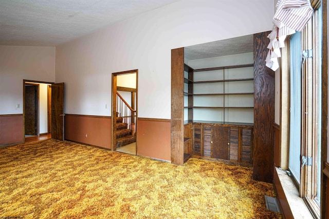 interior space featuring carpet, a textured ceiling, and built in features