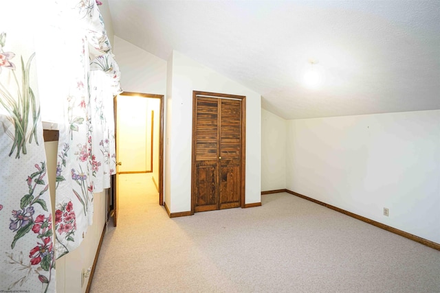 unfurnished bedroom featuring a closet, light colored carpet, and vaulted ceiling