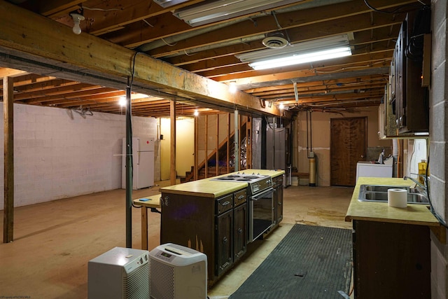 basement featuring washer and dryer, white refrigerator, and sink