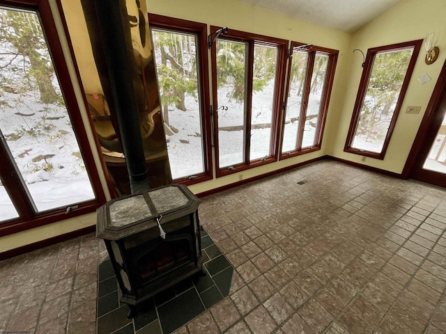 unfurnished sunroom featuring lofted ceiling and a wood stove