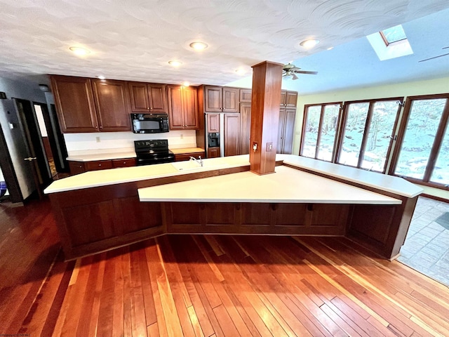 kitchen featuring black appliances, ceiling fan, dark hardwood / wood-style flooring, and a textured ceiling