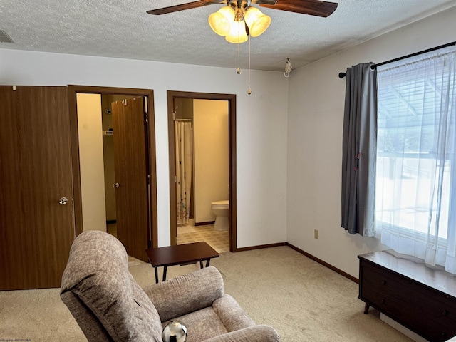 living area featuring ceiling fan, light colored carpet, and a textured ceiling