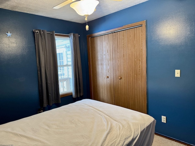 carpeted bedroom featuring ceiling fan, a textured ceiling, and a closet