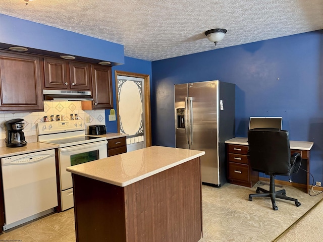 kitchen with a textured ceiling, decorative backsplash, a kitchen island, and white appliances