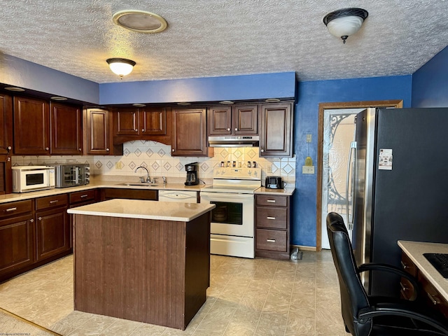 kitchen featuring a textured ceiling, white appliances, dark brown cabinetry, sink, and a center island