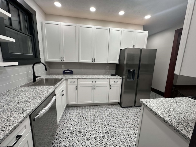 kitchen with backsplash, sink, light stone counters, white cabinetry, and stainless steel appliances