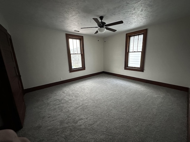 carpeted empty room featuring plenty of natural light, ceiling fan, and a textured ceiling