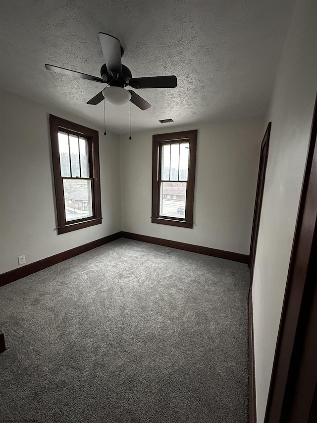 carpeted spare room featuring ceiling fan, a healthy amount of sunlight, and a textured ceiling