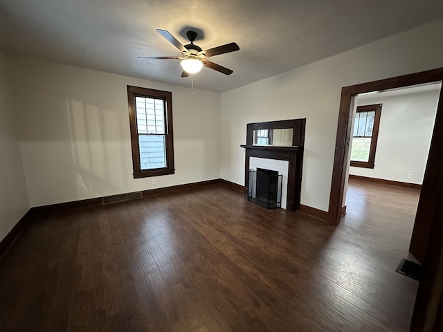 unfurnished living room featuring ceiling fan and dark wood-type flooring