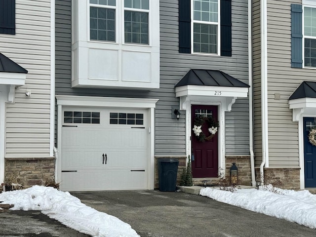 snow covered property entrance featuring a garage