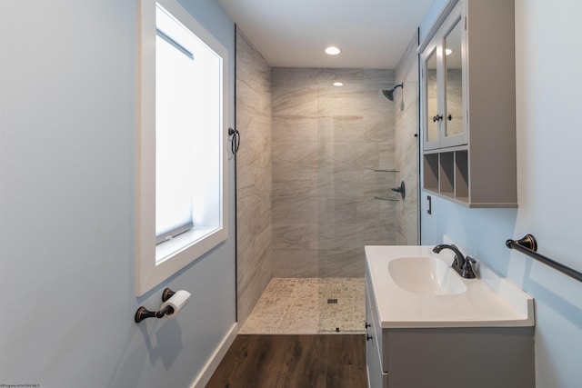 bathroom with hardwood / wood-style flooring, vanity, and a tile shower