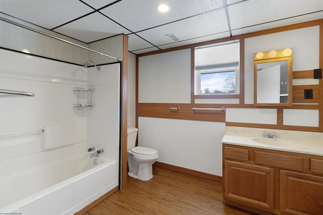 full bathroom with a drop ceiling, hardwood / wood-style floors, toilet, shower / tub combination, and vanity