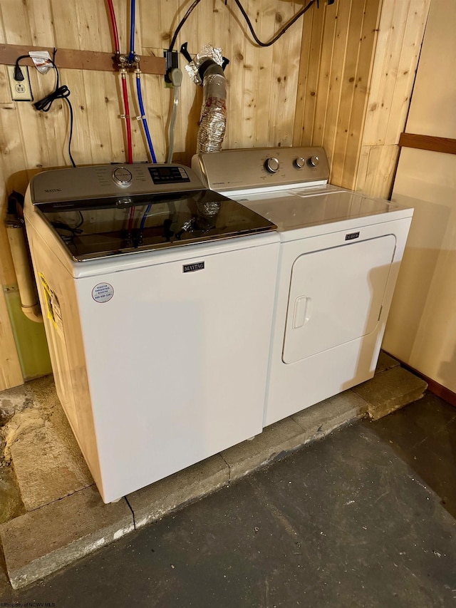 laundry room featuring wood walls and washing machine and dryer