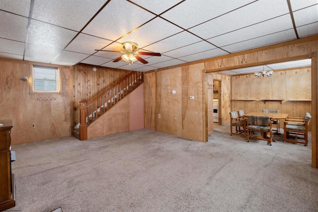 interior space featuring carpet, a paneled ceiling, ceiling fan, and wooden walls