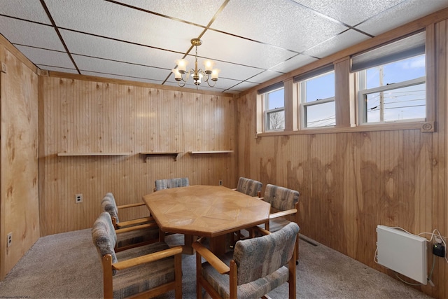 carpeted dining area featuring a paneled ceiling, radiator heating unit, and an inviting chandelier