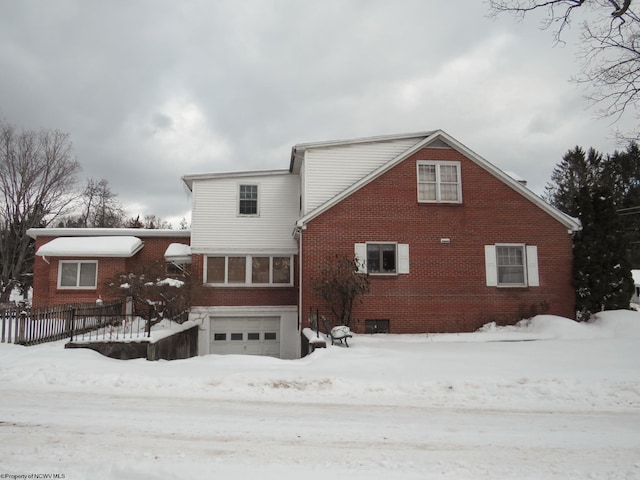 snow covered rear of property featuring a garage