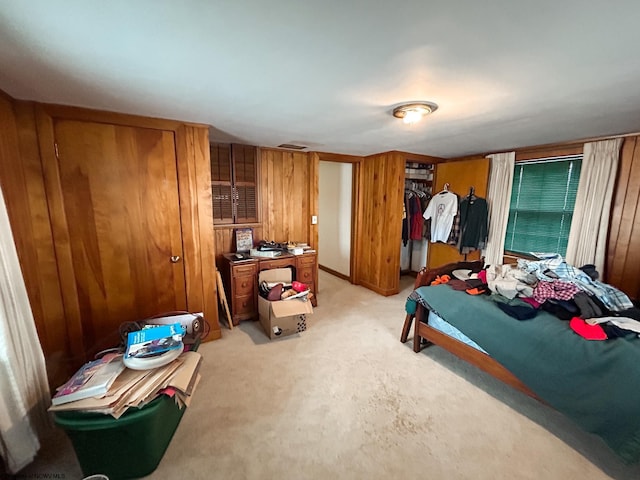 bedroom with wood walls and light carpet