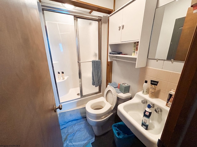 bathroom with toilet, a shower with door, tasteful backsplash, and sink