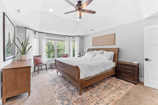 carpeted bedroom featuring ceiling fan, vaulted ceiling, and a tray ceiling