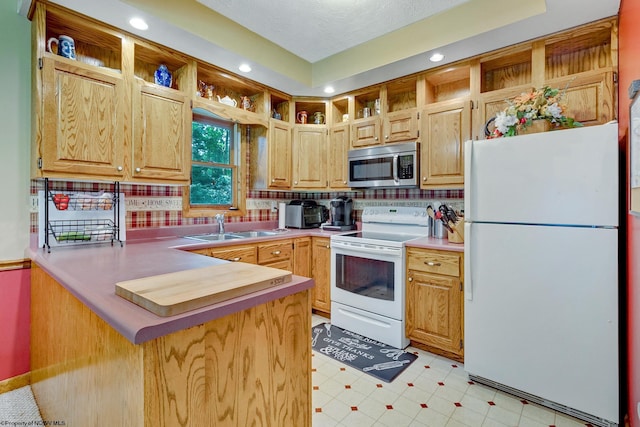 kitchen with white appliances, kitchen peninsula, backsplash, and sink