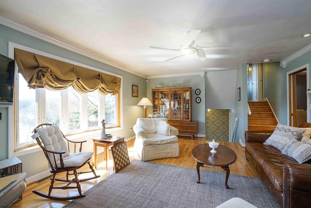 living area featuring a ceiling fan, a healthy amount of sunlight, wood finished floors, and crown molding