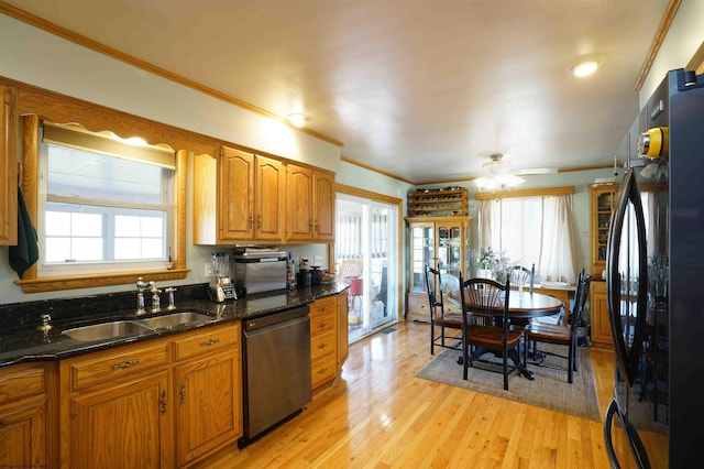 kitchen featuring a sink, stainless steel dishwasher, freestanding refrigerator, light wood-style floors, and brown cabinetry