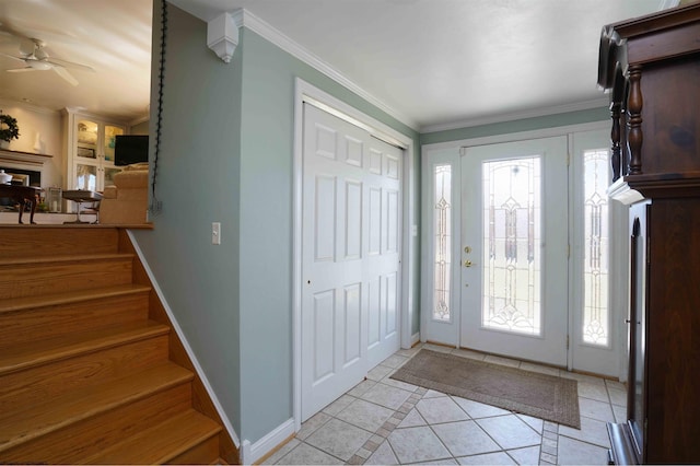 foyer entrance with crown molding, baseboards, stairs, light tile patterned flooring, and a ceiling fan