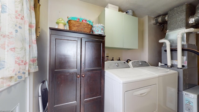 clothes washing area featuring washer and dryer and cabinets