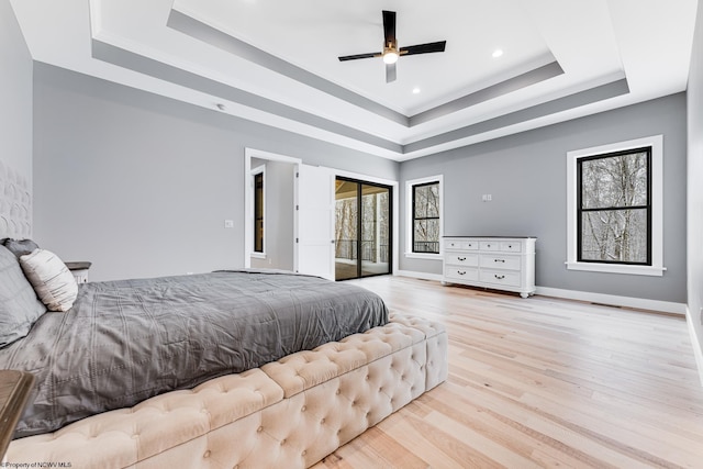 bedroom with light hardwood / wood-style floors, ceiling fan, access to outside, and a tray ceiling