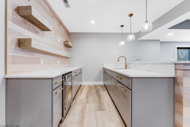 kitchen with tasteful backsplash, pendant lighting, gray cabinets, and light stone countertops