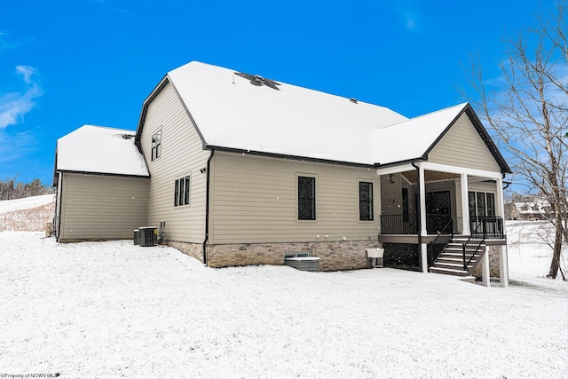 snow covered property featuring cooling unit and a sunroom