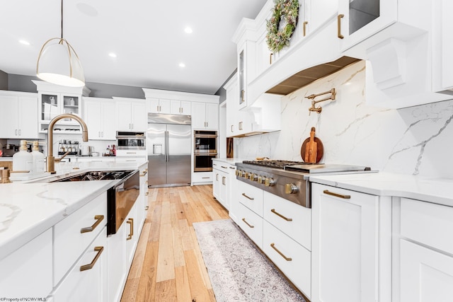 kitchen featuring stainless steel appliances, light wood-type flooring, pendant lighting, white cabinetry, and backsplash