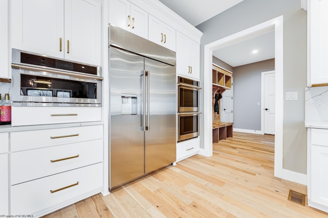 kitchen featuring white cabinets, appliances with stainless steel finishes, and light hardwood / wood-style flooring