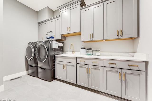 washroom with washing machine and dryer, light tile patterned flooring, cabinets, and sink