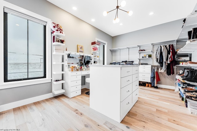 walk in closet featuring a notable chandelier and light hardwood / wood-style flooring