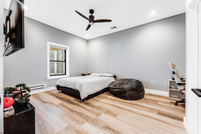 bedroom with hardwood / wood-style flooring, a baseboard heating unit, and ceiling fan