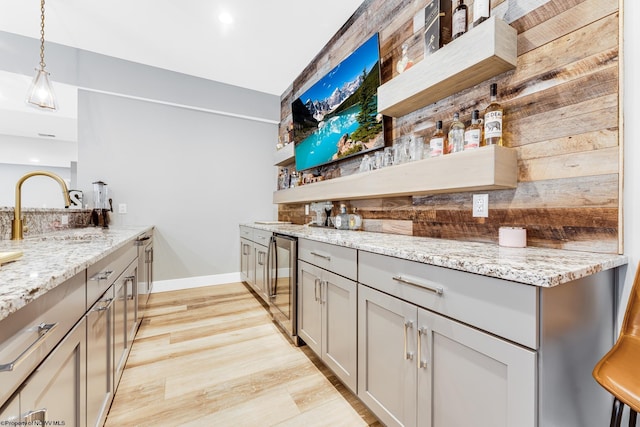 kitchen with wine cooler, gray cabinetry, light stone countertops, pendant lighting, and sink