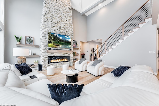 living room featuring a towering ceiling, a fireplace, and hardwood / wood-style flooring