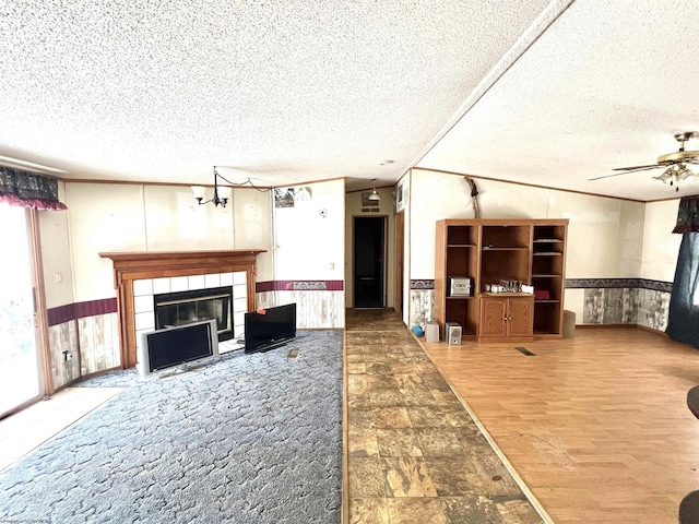 living room with hardwood / wood-style flooring, a textured ceiling, a tiled fireplace, and ceiling fan