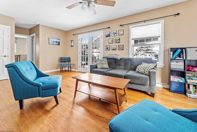 living room with french doors, baseboard heating, ceiling fan, and light hardwood / wood-style flooring