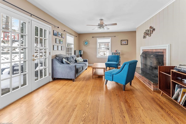 living room with a fireplace, ceiling fan, and light hardwood / wood-style floors