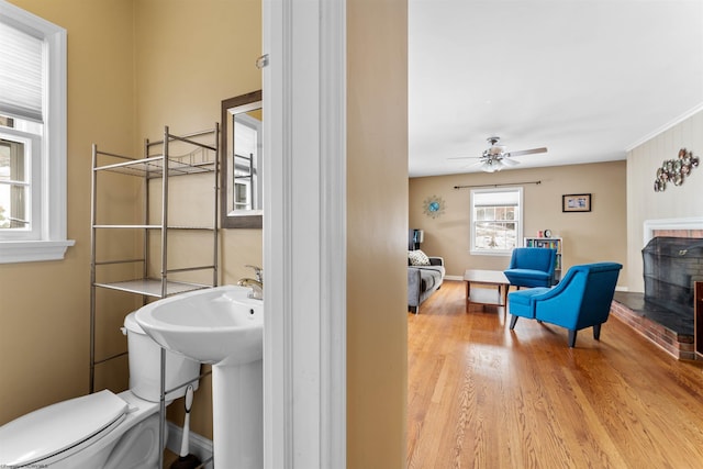 bathroom featuring ceiling fan, hardwood / wood-style floors, a fireplace, and toilet