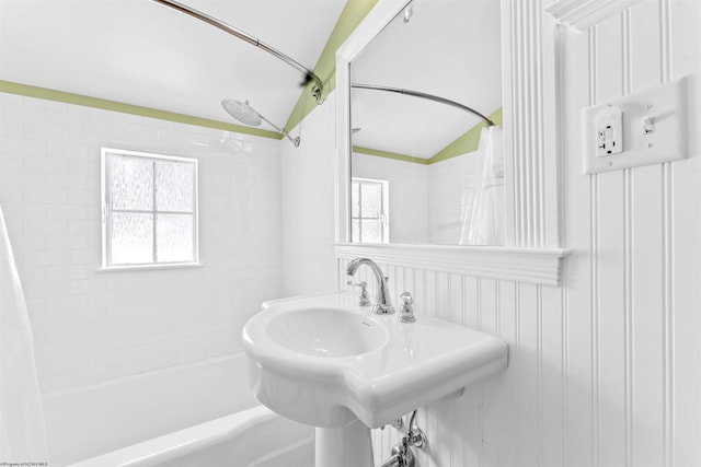 bathroom with shower / tub combo, vaulted ceiling, and sink