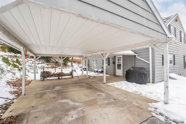 snow covered patio featuring grilling area and a carport