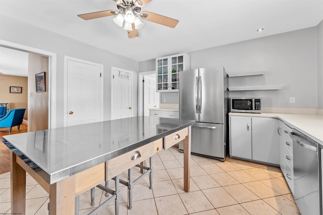 kitchen with white cabinets, appliances with stainless steel finishes, ceiling fan, and light tile patterned floors