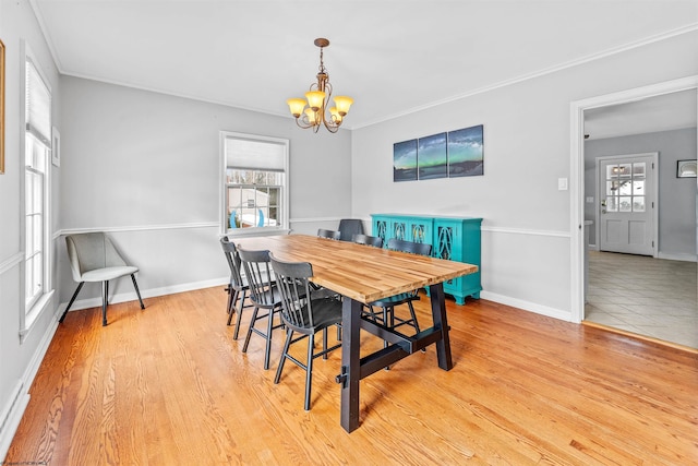 dining room featuring light wood-type flooring, a notable chandelier, crown molding, and a wealth of natural light