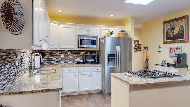 kitchen featuring light stone counters, stainless steel appliances, white cabinetry, and sink